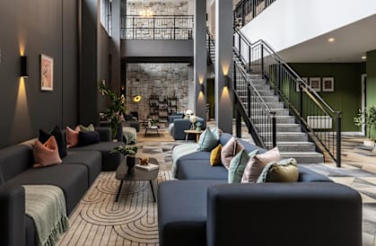 the lobby of a hotel with couches and a staircase