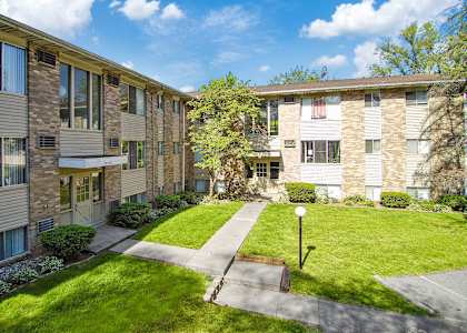 A sunny day at a residential building with green lawns and trees.
