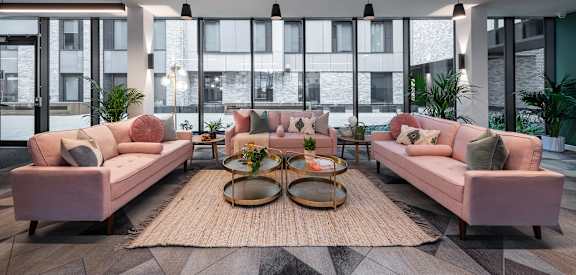 a living room with pink couches and a rug