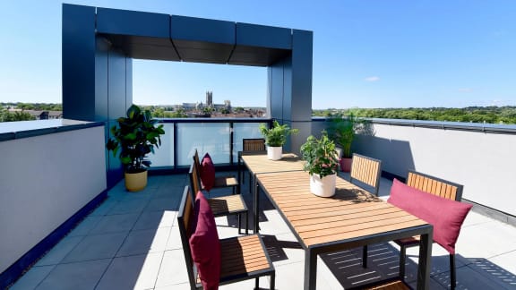 a roof top terrace with a wooden table and chairs