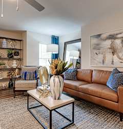 A living room with a brown couch, a coffee table, and a painting on the wall.