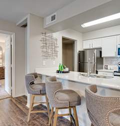 A kitchen with a breakfast bar and a dining table with chairs.