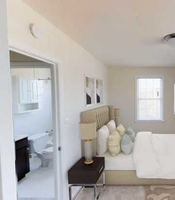 bedroom with bed, tv, window view of bathroom and plush carpeting at jetu apartments in washington dc