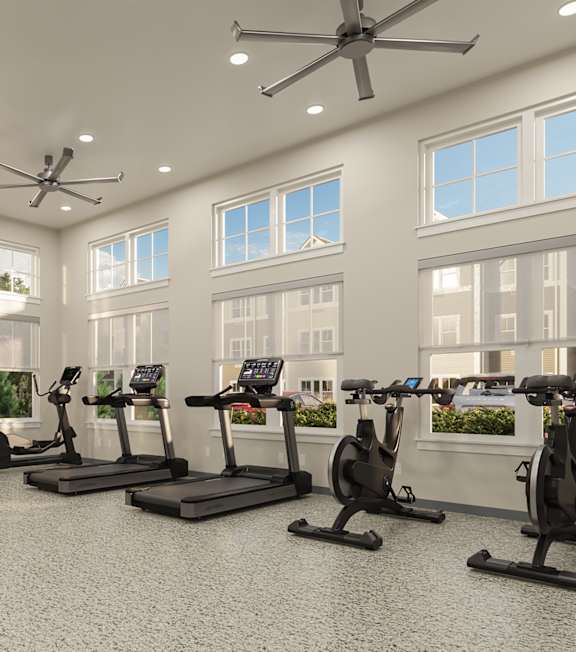 A spacious gym with a variety of exercise equipment and a ceiling fan.