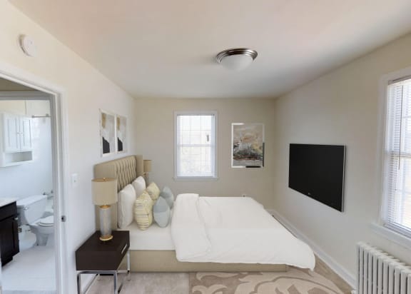 bedroom with bed, tv, window view of bathroom and plush carpeting at jetu apartments in washington dc