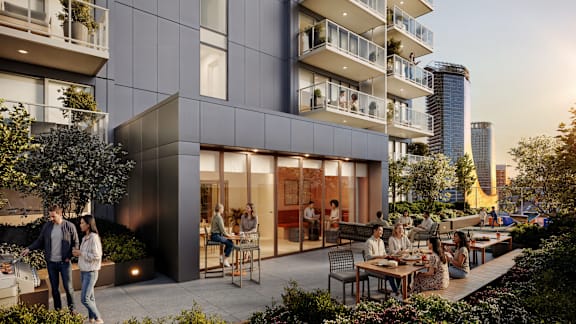 A modern apartment complex with people enjoying the outdoor seating area.