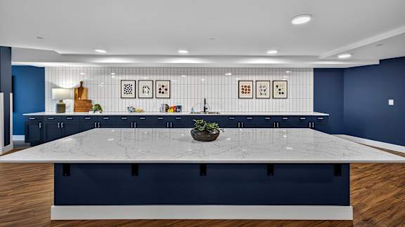 A large white table is in the middle of a room with blue walls and wooden floors.