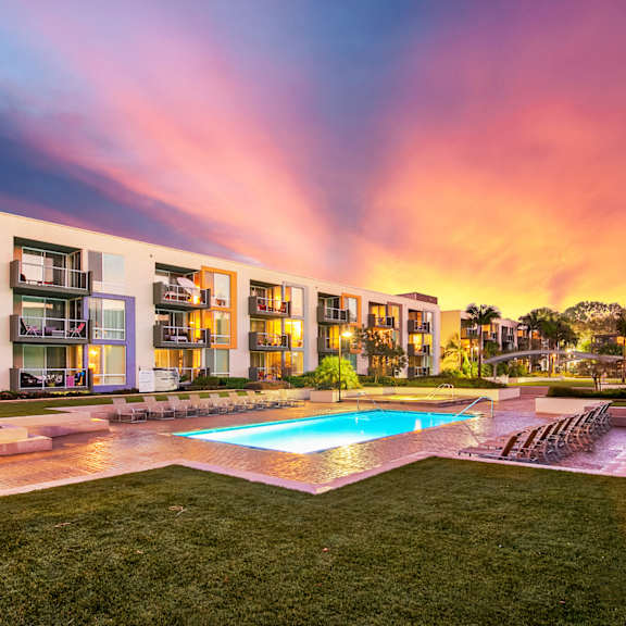 A modern apartment complex with a pool in the foreground.