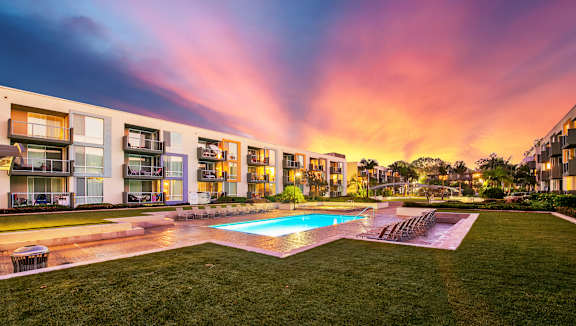 A modern apartment complex with a pool in the foreground.