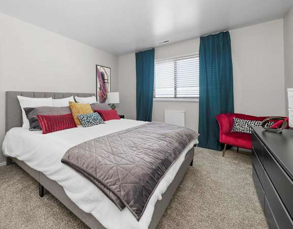 A bedroom with a large bed and a red chair.