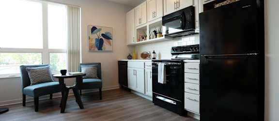 a kitchen with black appliances and white cabinets and a table with two chairs