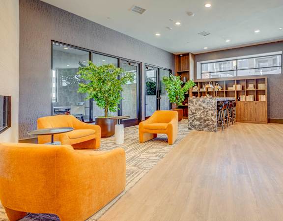 A spacious waiting area with orange chairs and a wooden floor.