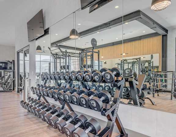 A gym with a variety of equipment including dumbbells and weight machines.