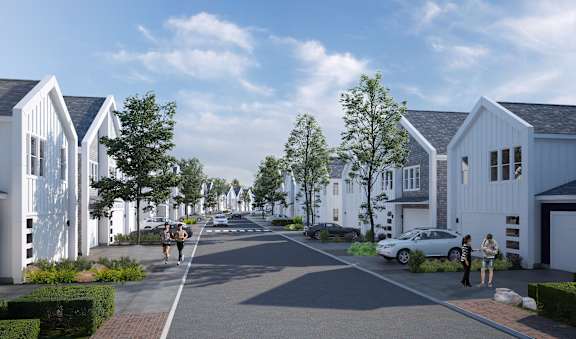 A street view of a residential area with houses on both sides and cars parked on the side of the road.