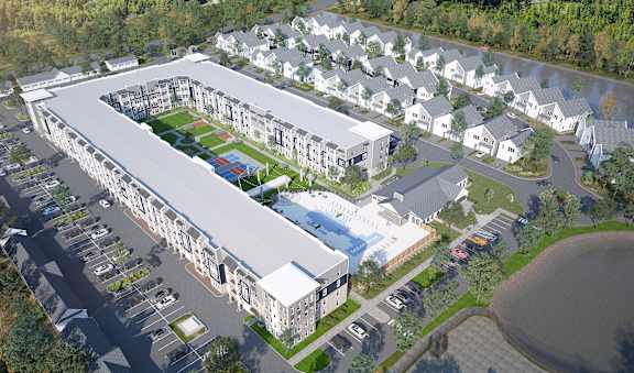 A large white building with a green roof is surrounded by smaller white houses.