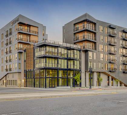 A modern building with a glass entrance and balconies on the second floor.