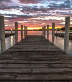 a dock on a lake with a sunset in the background