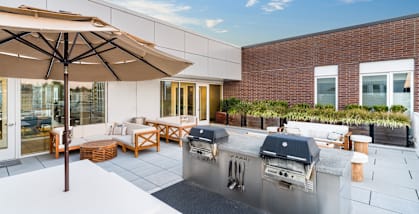 A patio with a grill and seating area.