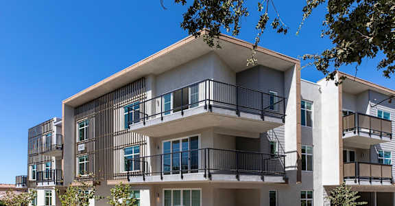 A modern apartment building with balconies and multiple stories.