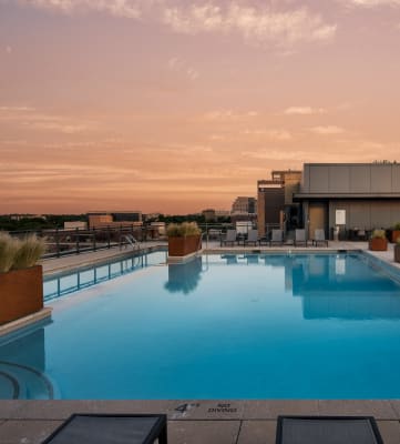 a rooftop pool with lounge chairs and a building in the background