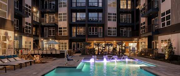 a swimming pool in front of an apartment building at night