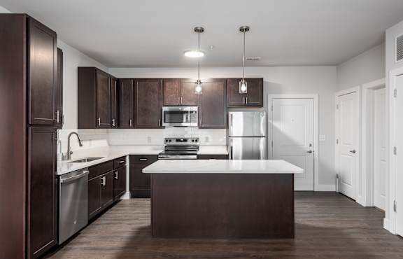 A modern kitchen with dark brown cabinets and white countertops.