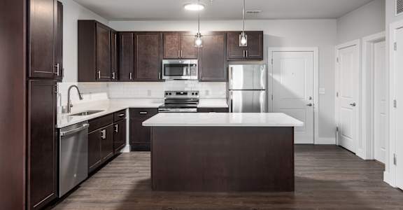 A modern kitchen with dark brown cabinets and a white countertop.