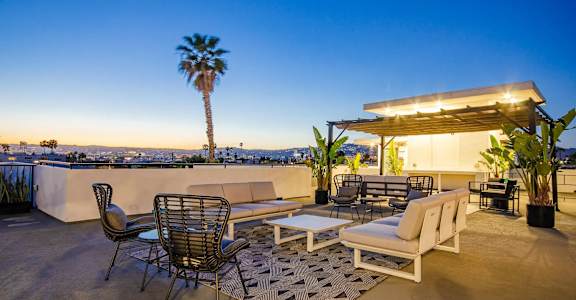 A patio with a table and chairs overlooking a cityscape at dusk.