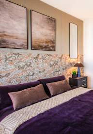 A bedroom with a bed, two nightstands, and a stone wall.