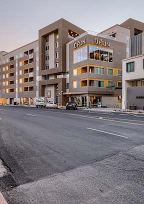 an empty street in front of an apartment building with palm trees