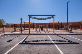 a dog park with a gate and a building in the background