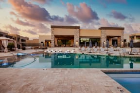 a resort style pool with lounge chairs and umbrellas