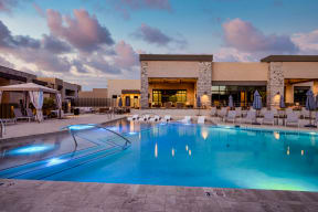 a swimming pool with lounge chairs and umbrellas in front of a building