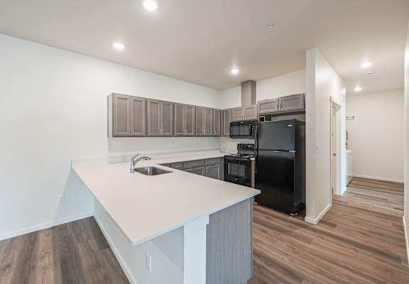 A kitchen with a black refrigerator and wooden cabinets.