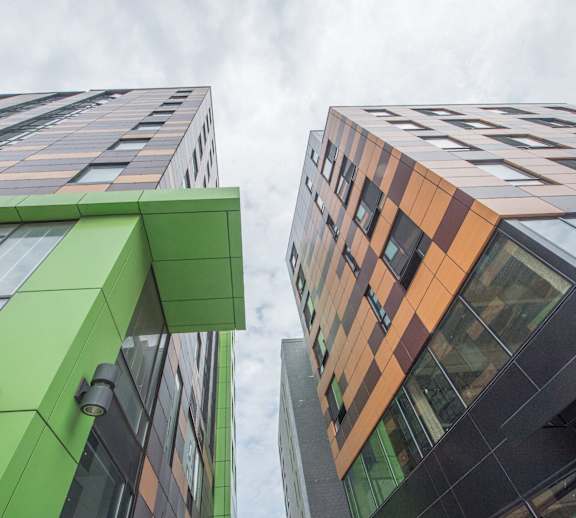 Two modern buildings with glass windows and a green exterior.