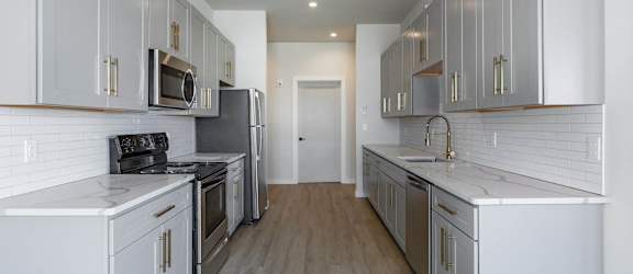 A modern kitchen with wooden shelves and black countertops.