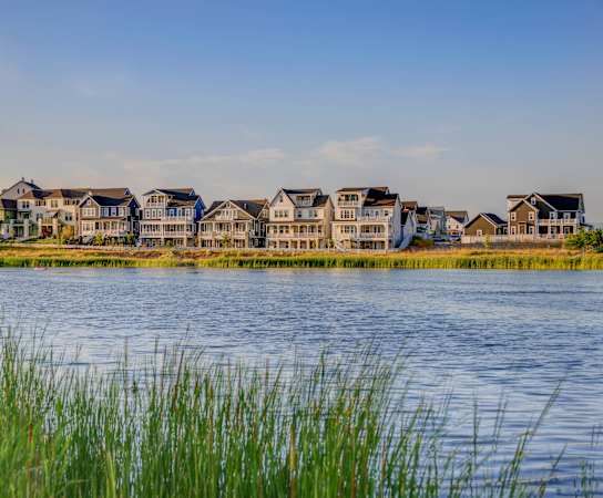 A row of houses are reflected in the water in front of them.