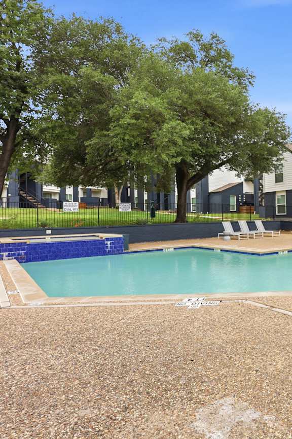 A swimming pool surrounded by a fence and chairs.