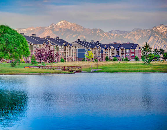 A serene lake in front of a mountain range with a building in the foreground.