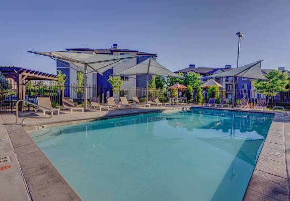 A large swimming pool in front of a building with a blue sky in the background.