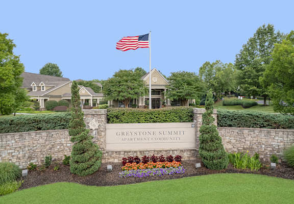 The sign for the Greystone Summit Apartment Community is in front of a house.