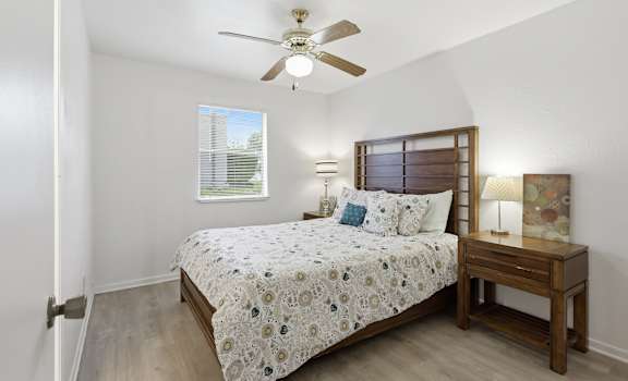 A bedroom with a bed, nightstand, and window.