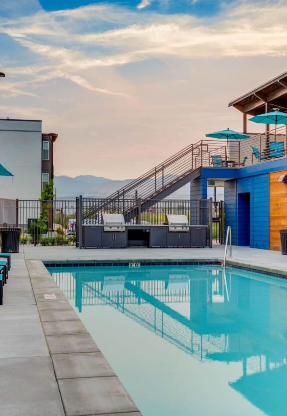 the pool and poolside deck of a blue building with a swimming pool and stairs