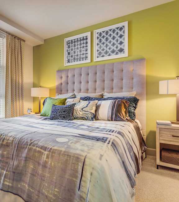 A bedroom with a bed, nightstand, and window.