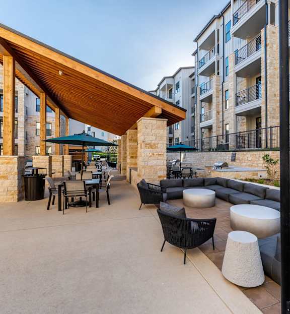 A patio area with a wooden roof and black furniture.