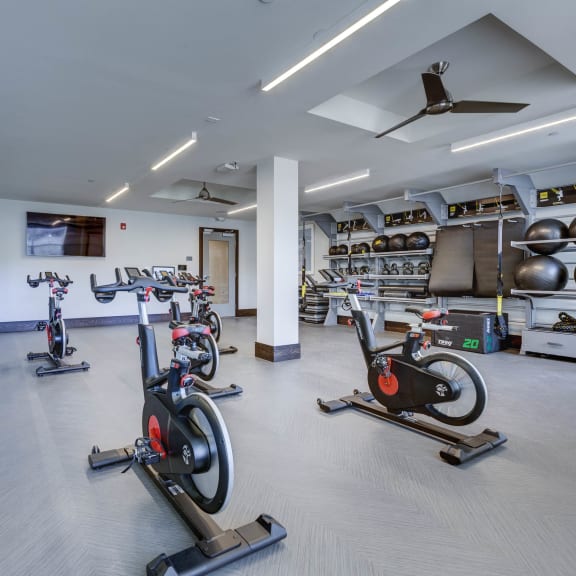 a gym with various exercise bikes and weights on the floor