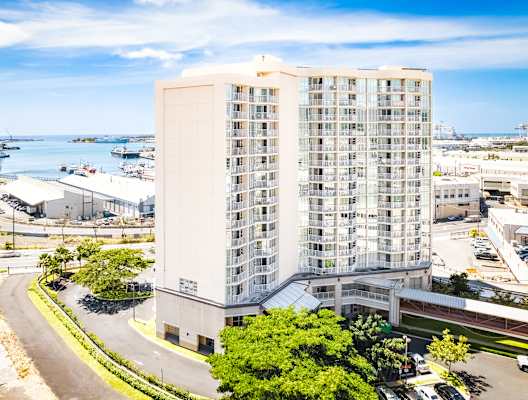an aerial view of a tall building in a city with a body of water in the background