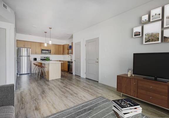 a living room with a tv and a kitchen with stainless steel appliances