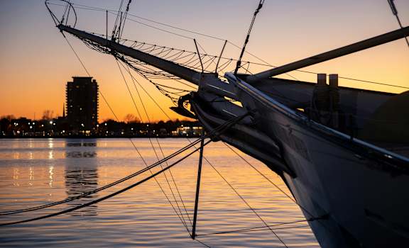 A sailboat is docked in the water with its mast extended.