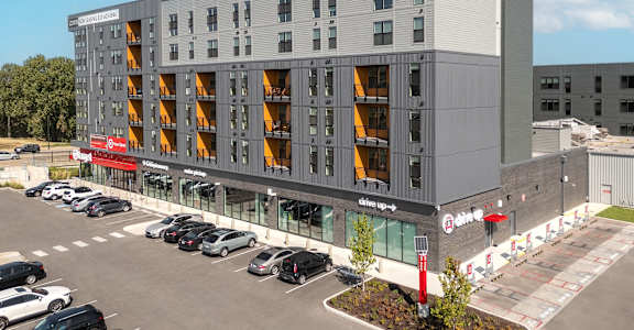 a large apartment building with cars parked in front of it at The Edwin on Grand Apartments, Missouri
